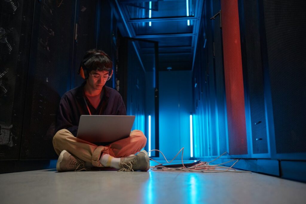 מהנדס רשתות עובד על מחשב נייד בחדר שרתים של מרכז נתונים