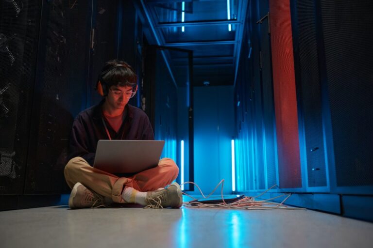 מהנדס רשתות עובד על מחשב נייד בחדר שרתים של מרכז נתונים
